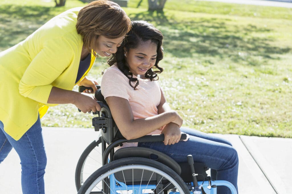 A mother pushes a daughter in a wheelchair.